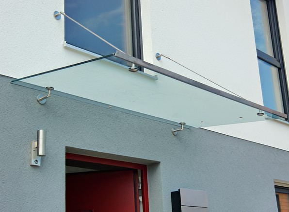 Modernes Glasvordach mit Zugstangen über einer Haustür