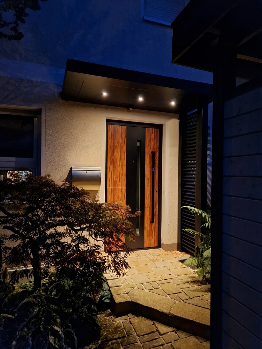 Kubisches Vordach mit Sprossen-Seitenteil am Abend mit eingeschalteter Beleuchtung