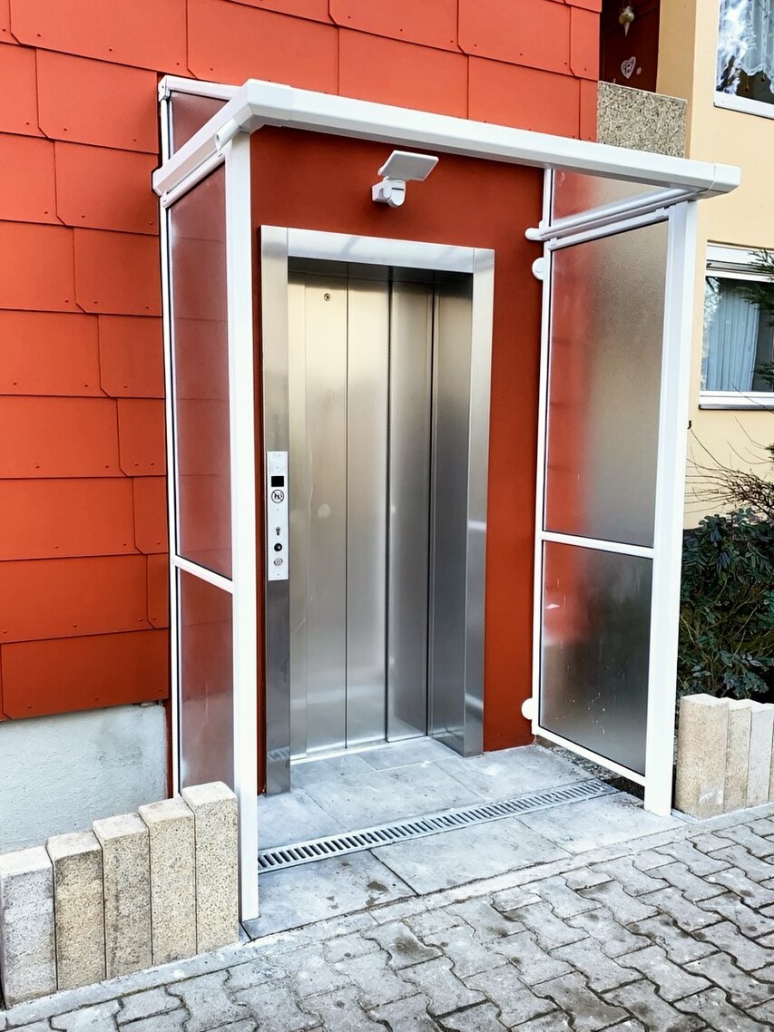 Aluminium-Pultvordach mit Acrylglas und zwei rechteckigen Seitenblenden vor Aufzugseingang